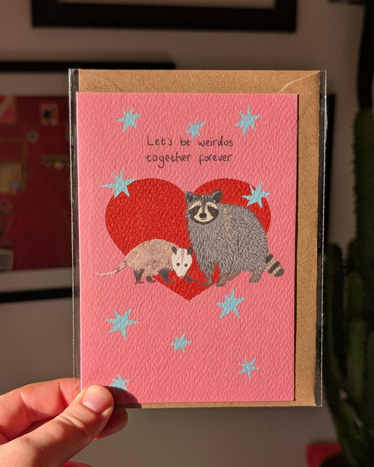 Illustrated funny anniversary card. Raccoon and opossum - let's be weirdos together forever